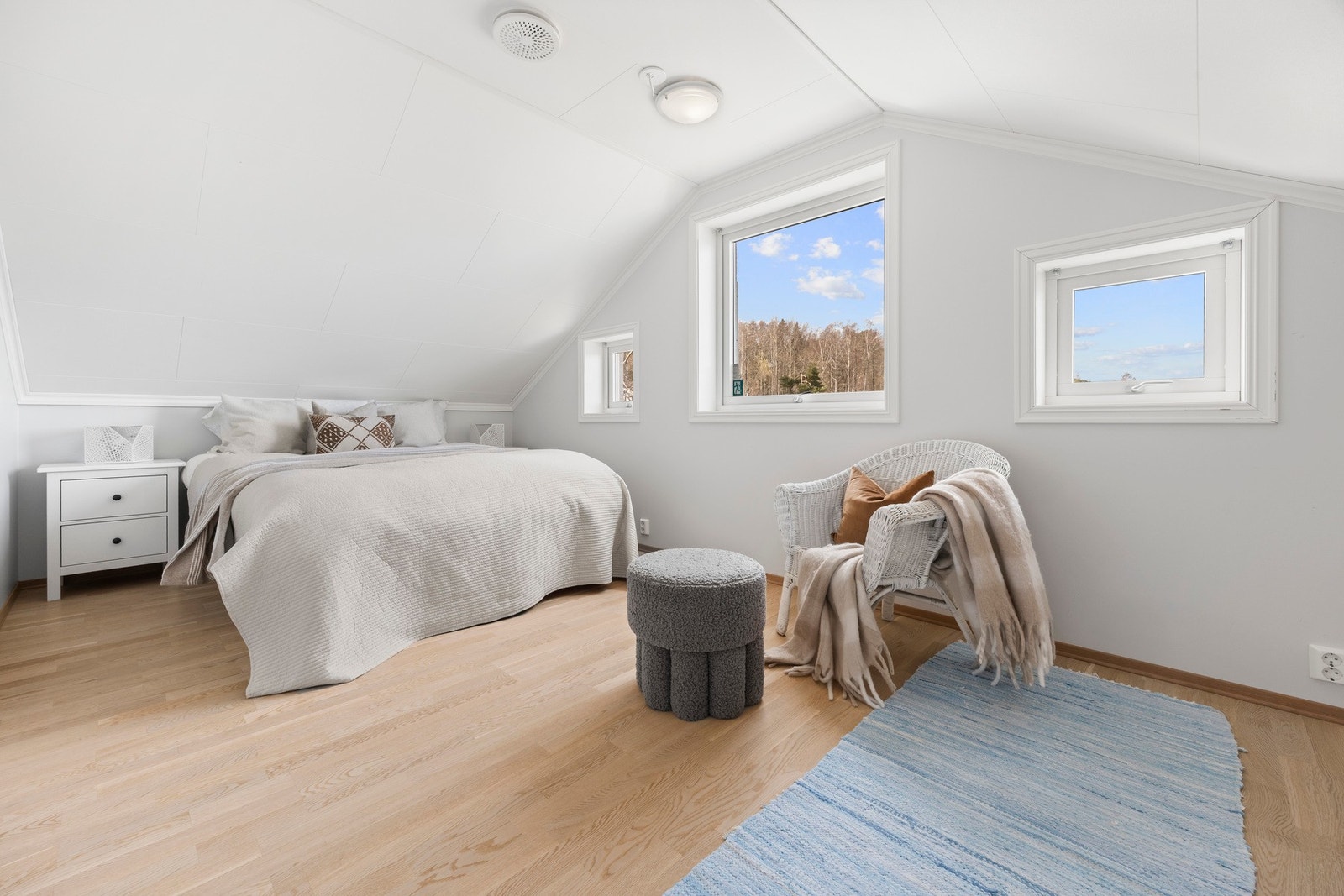 Lyst og romslig soverom med skråtak og store vinduer som slipper inn naturlig lys. Galleribilde