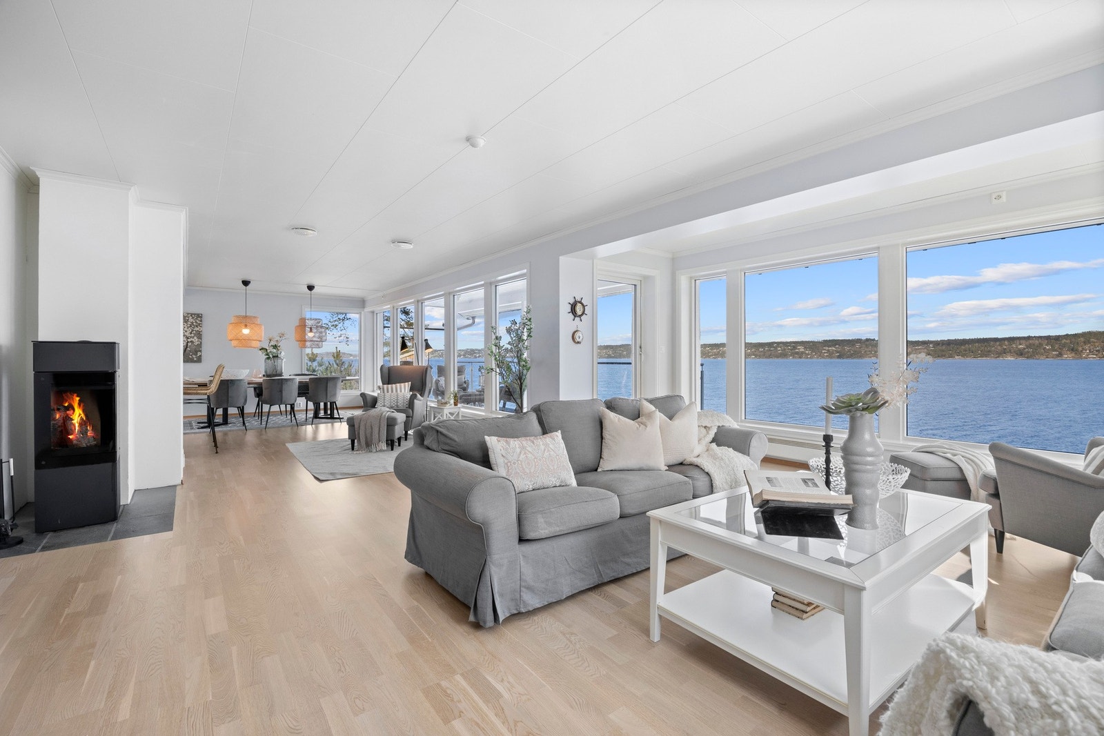 Romslig stue med store vinduer og peis, åpen løsning mot spisestue og fantastisk utsikt over vannet. Galleribilde