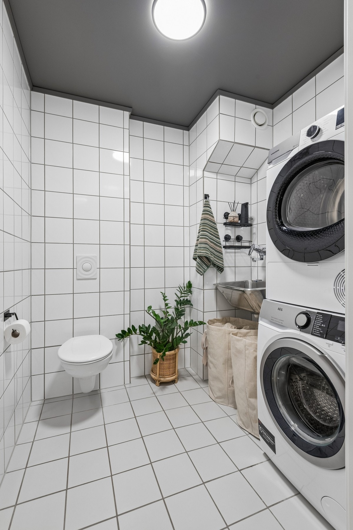 Separat vaskerom med utslagsvask, vegghengt toalett og opplegg for vaskemaskin. Galleribilde