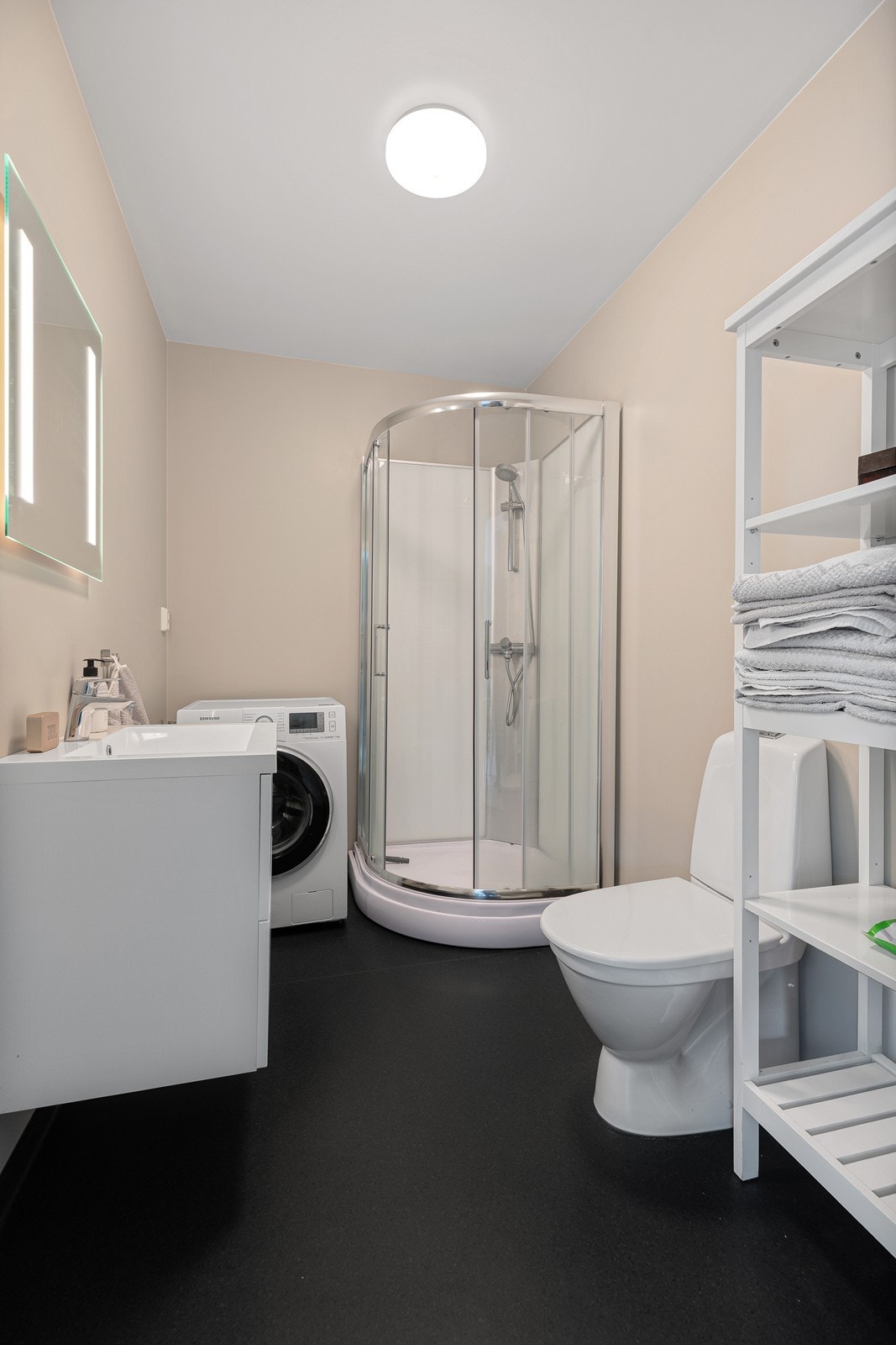 Praktisk bad med slitesterkt vinylbelegg og varmekabler på gulvet. Badet er innredet med nedfelt servant, toalett, dusjkabinett, og har opplegg for vaskemaskin Galleribilde