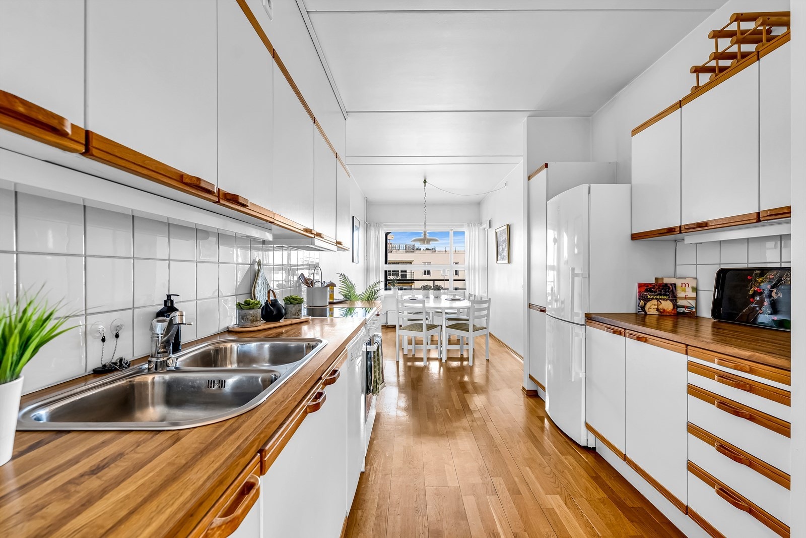 Kjøkkeninnredning med slette fronter og laminerte benkeplater, kombinert med flislagt backsplash. Galleribilde