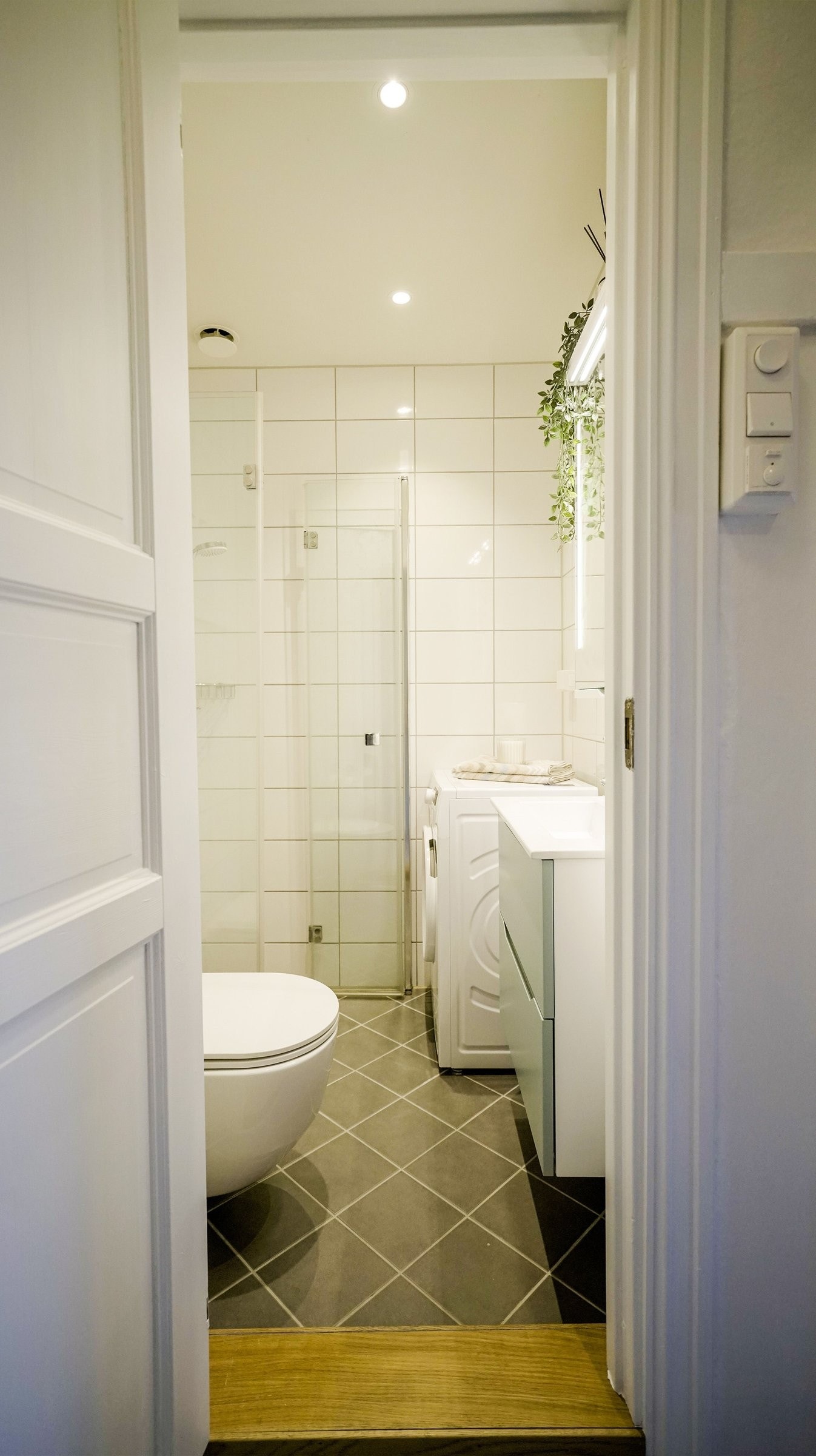 Badet har fliser på vegger og gulv, og malt himling med downlights i taket. Galleribilde