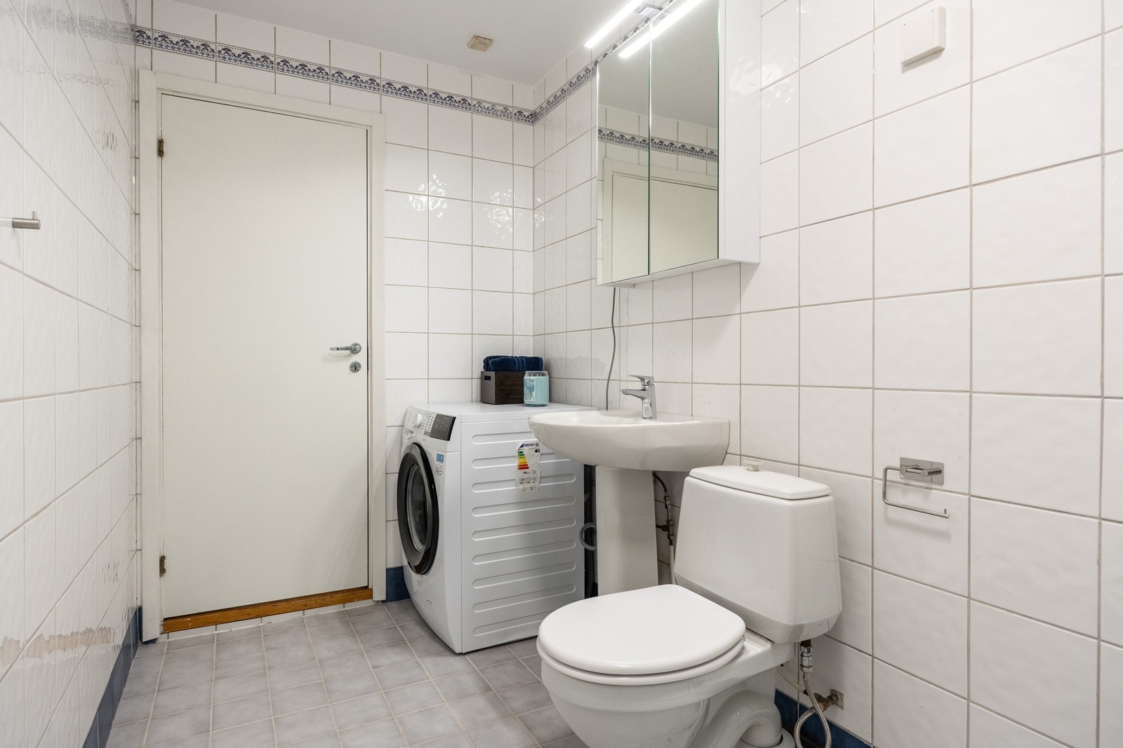 Badet er innredet med gulvstående servantinnredning, speil med overlys, dusjkabinett med dusjarmatur, samt gulvstående toalett. Galleribilde