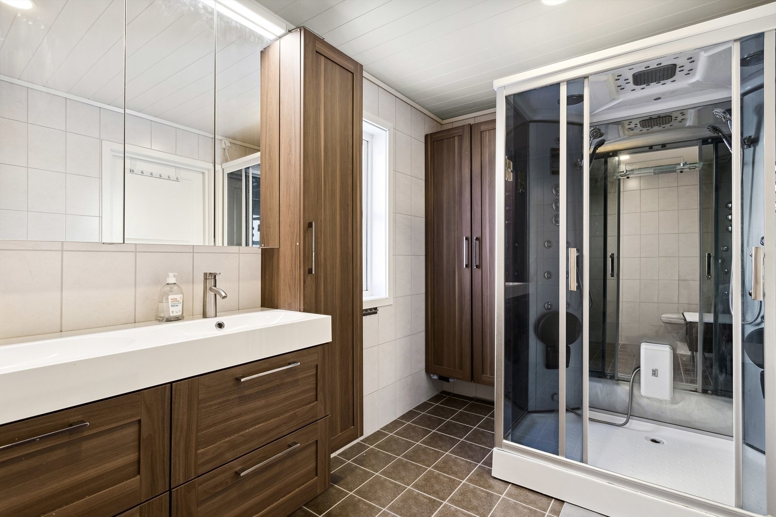 Baderommet er ca 7,7 m² og har flis på gulv og vegg, trepanel i himling. Oppgradert i 2014. Badet inneholder dusjkabinett, gulvmontert toalett samt innredning med servant Galleribilde