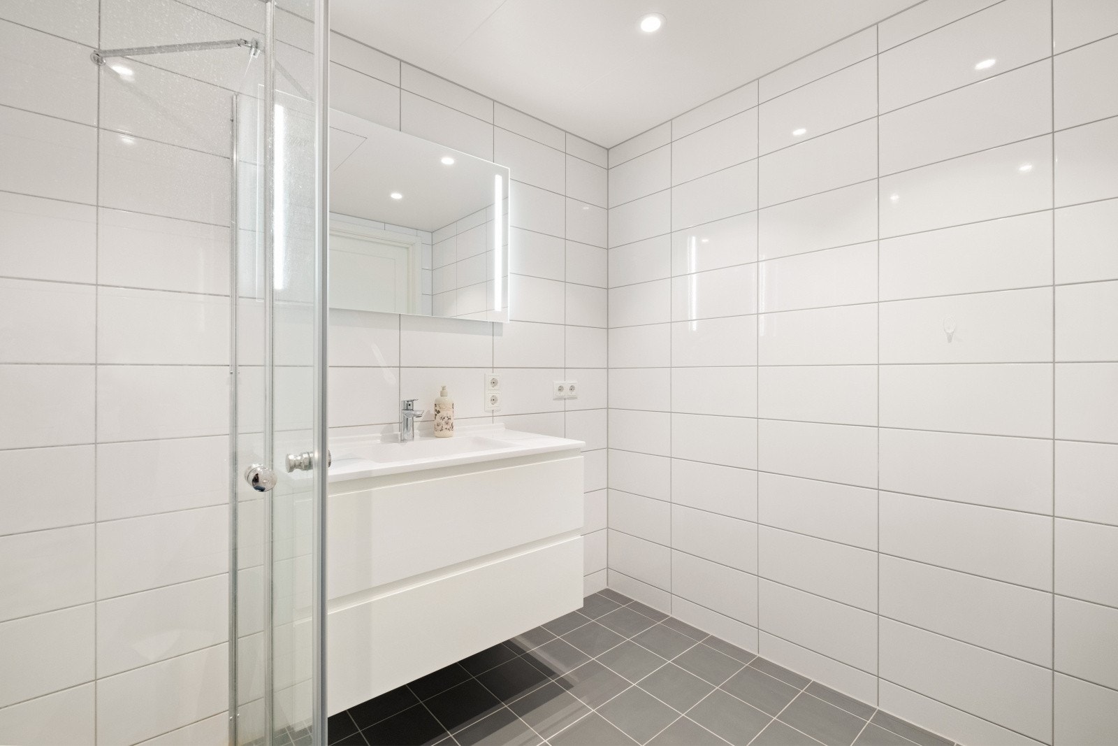 Badet er utstyrt med nedfelt servant, vegghengt wc og dusjdører samt opplegg for vaskemaskin. Galleribilde
