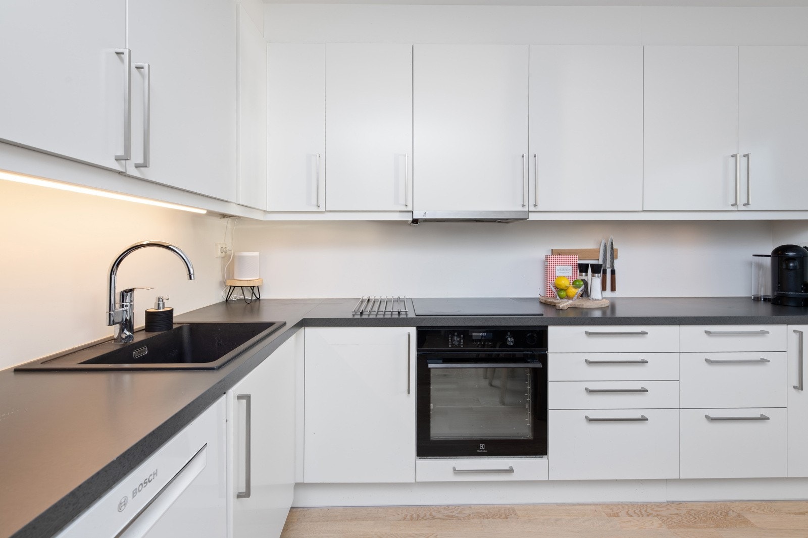 Laminerte benkeplater med nedfelt oppvaskkum i svart kompositt. Integrerte hvitevarer: stekeovn, koketopp, oppvaskmaskin medfølger Galleribilde