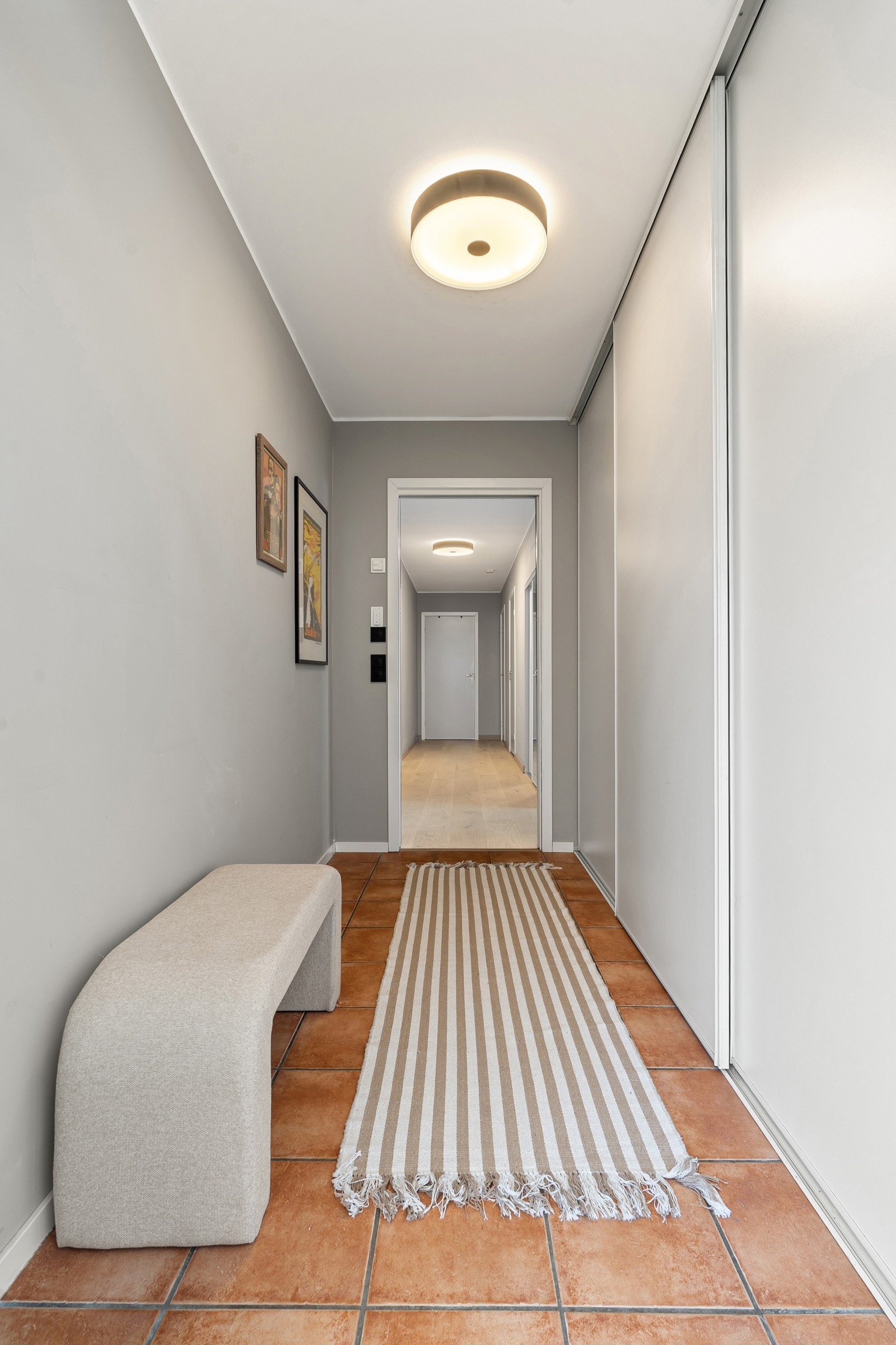 Velkommen inn! Stor, flislagt gang med skyvedørsgarderobe.