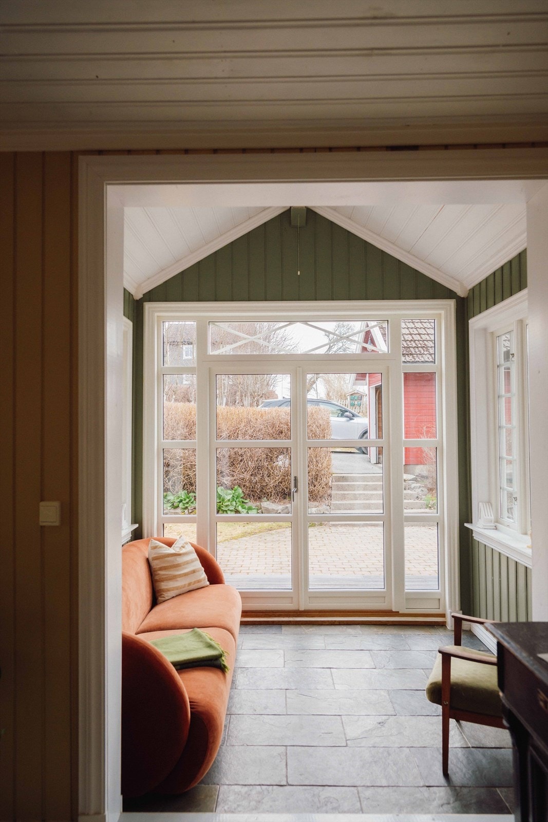 Her er det flislagt gulv med varme, gulmalte vegger og mønet tak. Det er store vinduer i alle retninger og tofløyet glassdør ut. Galleribilde