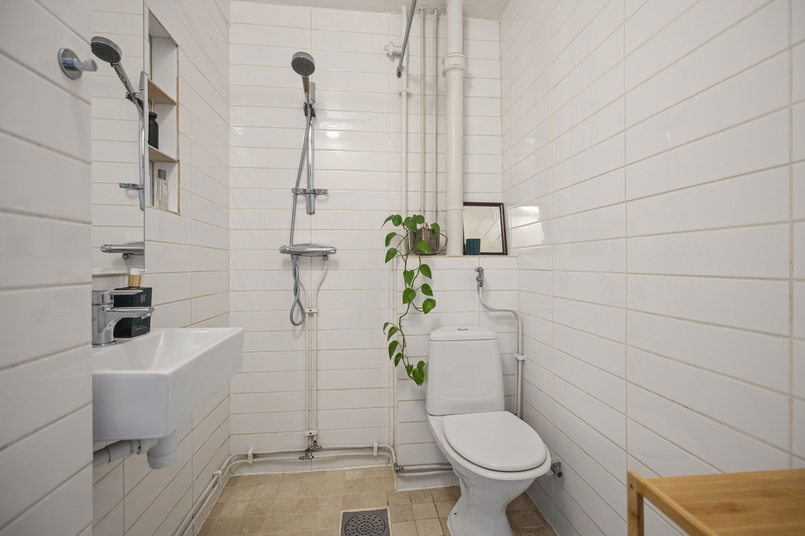 Badet har flislagte vegger, åpen dusj, wc og servant med trebord til siden. Galleribilde