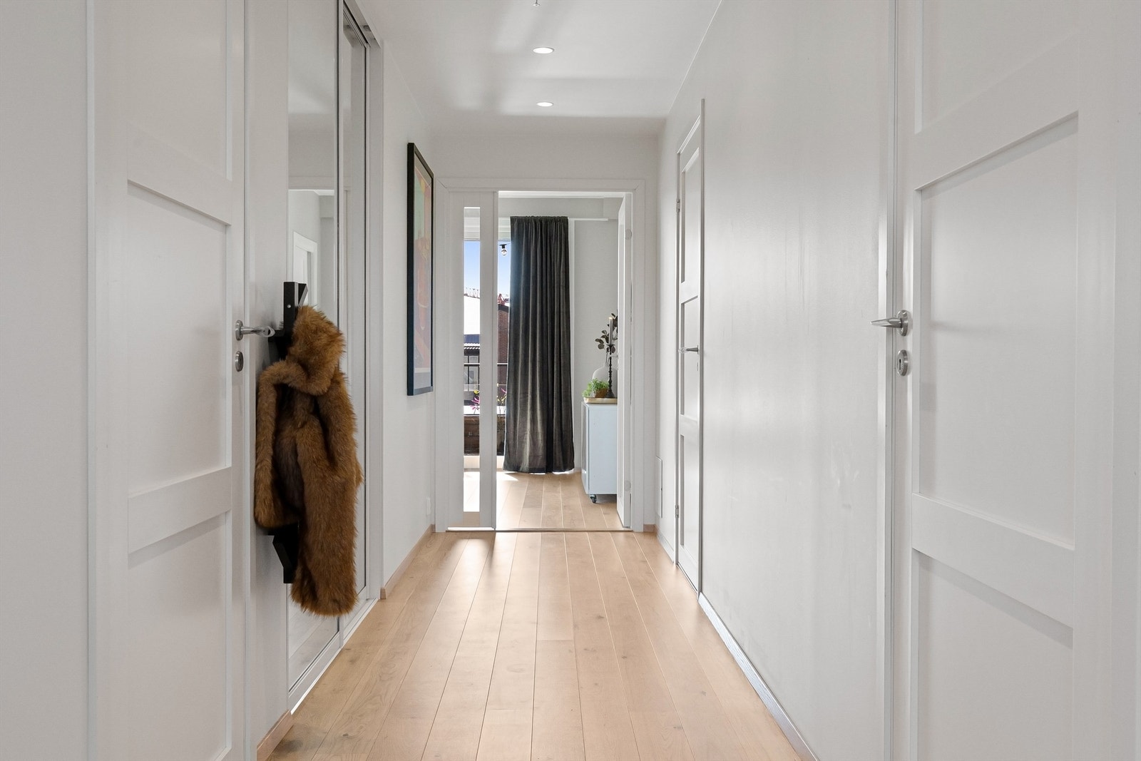 En skyvedørsgarderobe med speilfronter i gangen gir gode oppbevaringsmuligheter for yttertøy. Galleribilde
