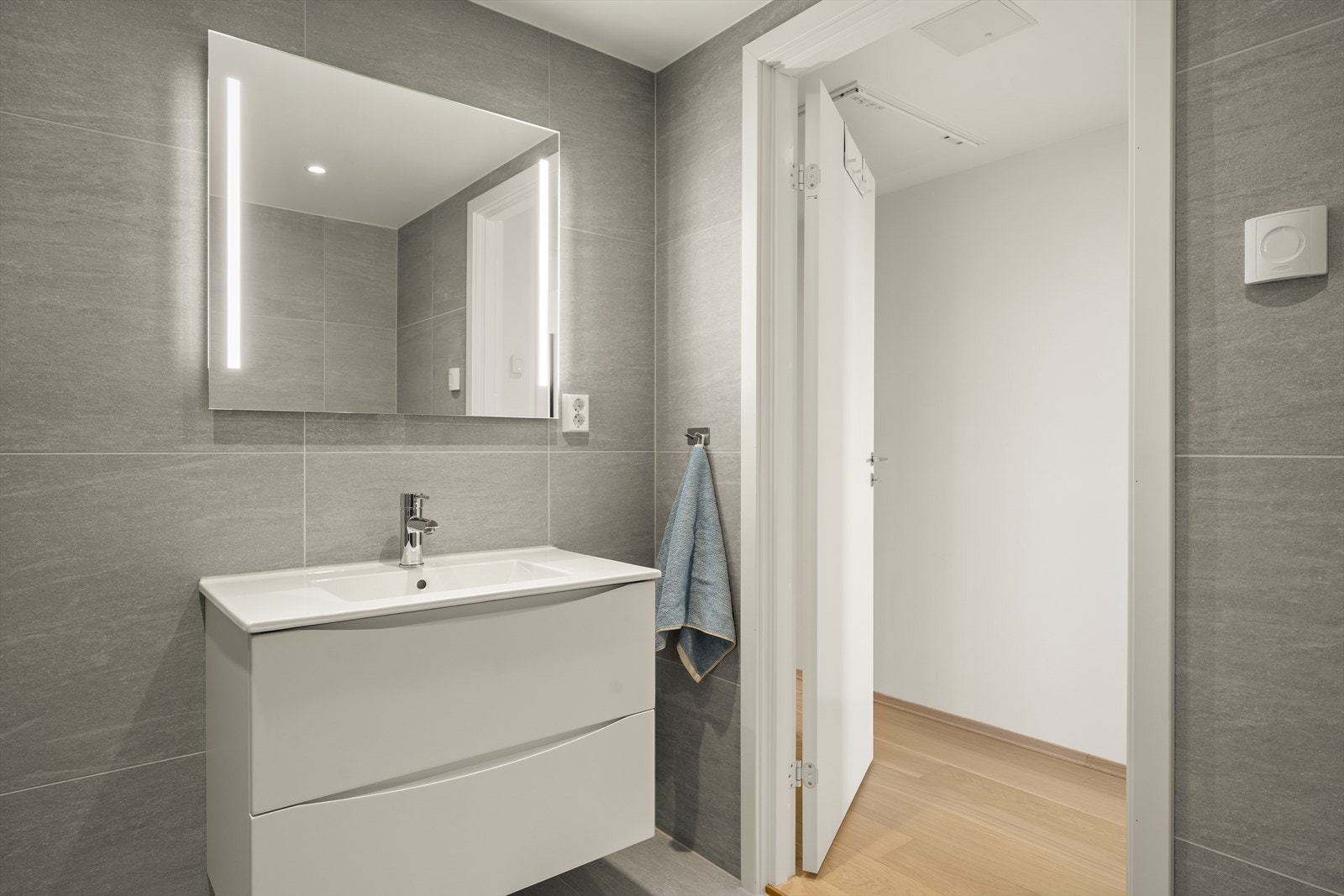 Badet er innredet med servantinnredning med slette, lyse fronter samt overhengende speil med belysning. Galleribilde
