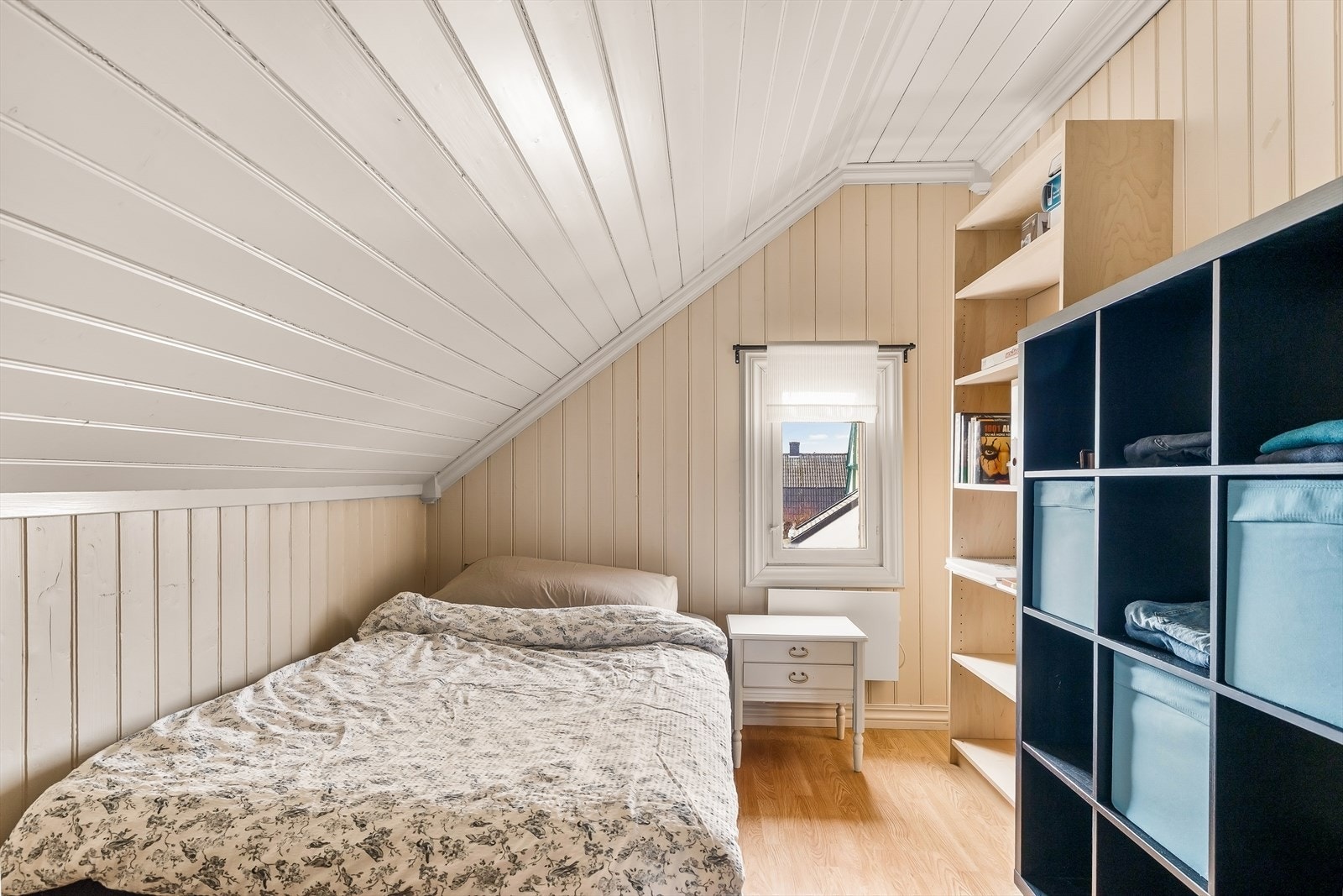 Koselig soverom med laminat på gulv, og malt panel i tak og på veggene. Galleribilde