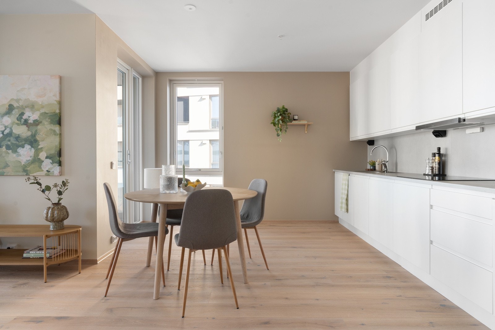 Gjennomført kjøkken med lyse, glatte fronter og integrerte hvitevarer som medfølger handelen.