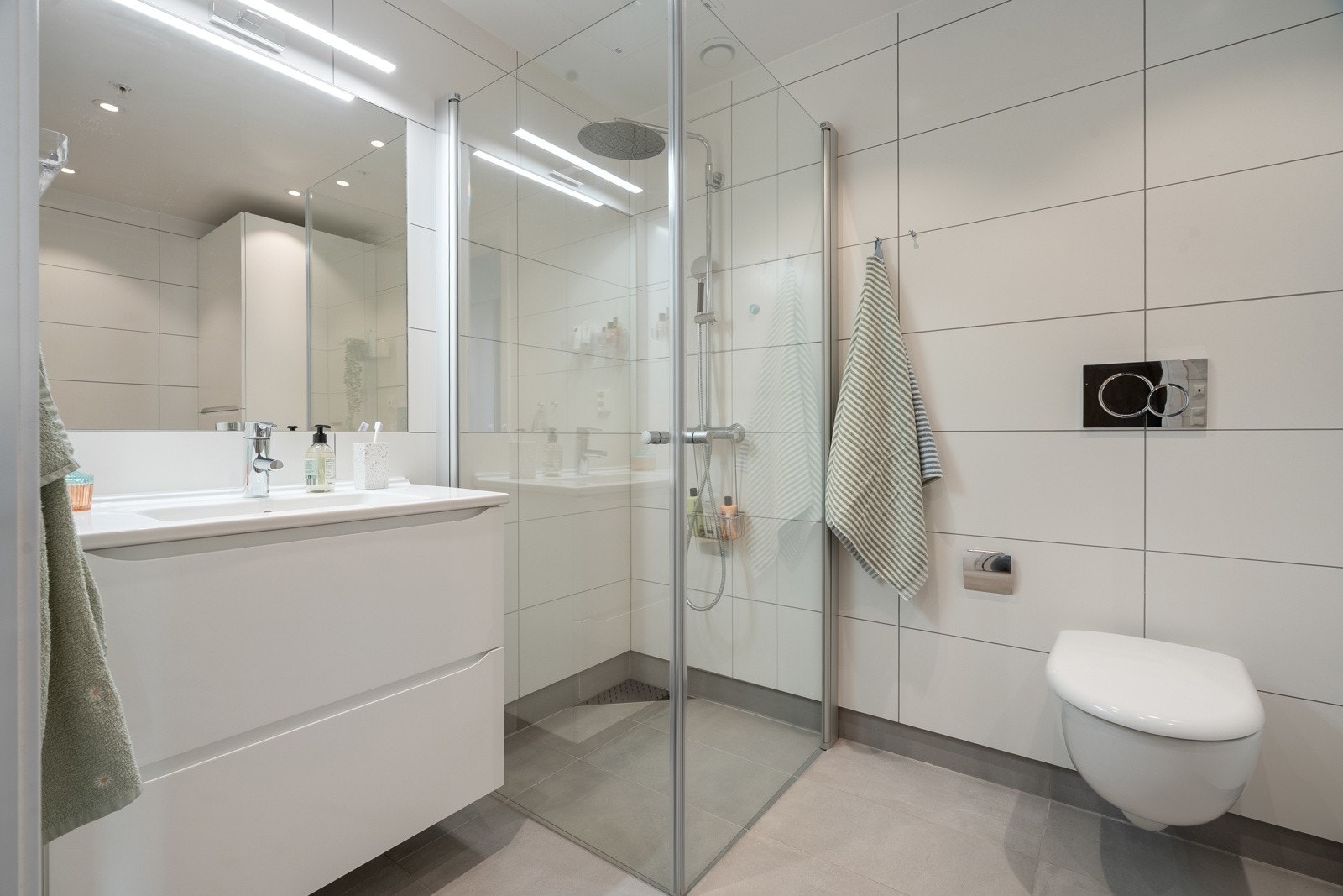 Badet er lyst og delikat innredet med hvite fronter - Komplett flislagt og med dusjhjørne med innfellbare dusjvegger.