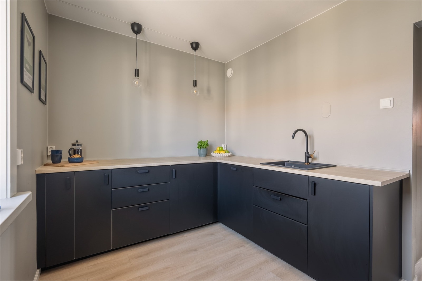 Kjøkkeninnredning fra IKEA med glatte, sorte fronter, benkeplate med laminert overflate og kjøkkenvask i sort utførelse. Galleribilde