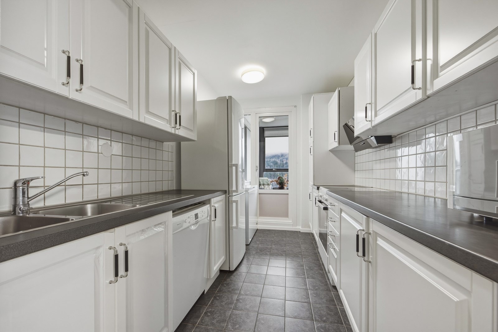 Kjøkken med profilerte fronter nye i 2025, samt benkeplate i laminat og flislagt over kjøkkenbenk Galleribilde