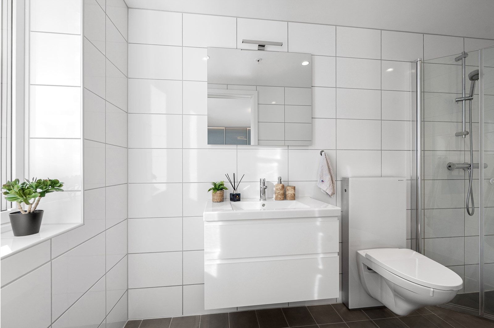 Det private badet har dusj med innfellbare dører i herdet glass og elektrisk gulvvarme. Galleribilde