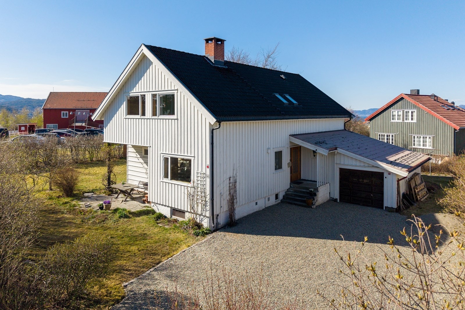 Tomten har gruslagt innkjørsel, garasje og flere biloppstillingsplasser. Galleribilde