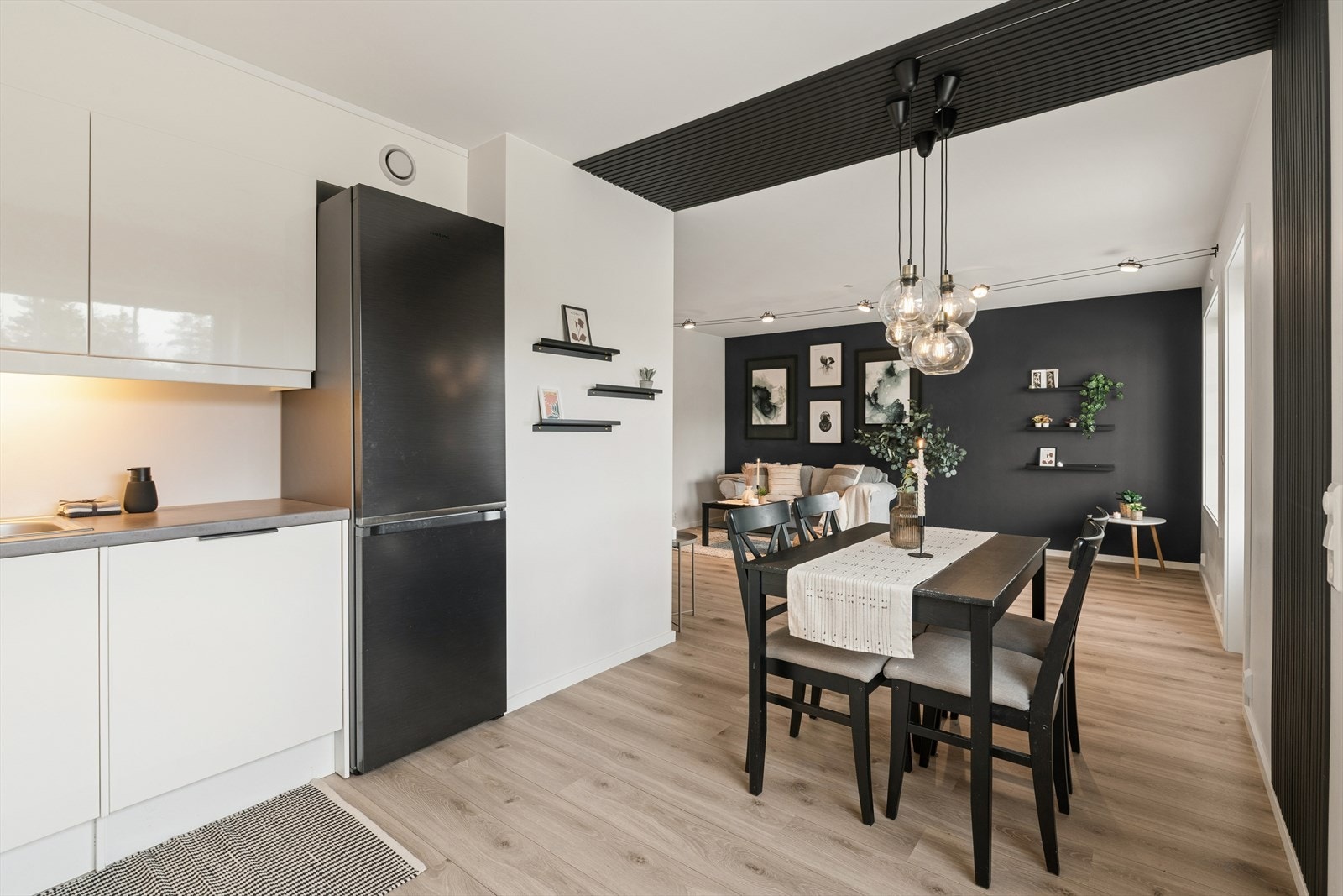 Den åpne løsningen mellom kjøkken og stue skaper en sosial og luftig atmosfære, med en naturlig plass for spisebordet. Galleribilde