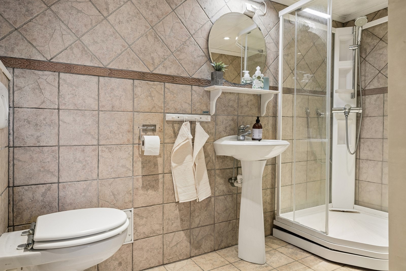 Badet er innredet med dusjkabinett, vegghengt toalett, opplegg for vaskemaskin og servant. Galleribilde