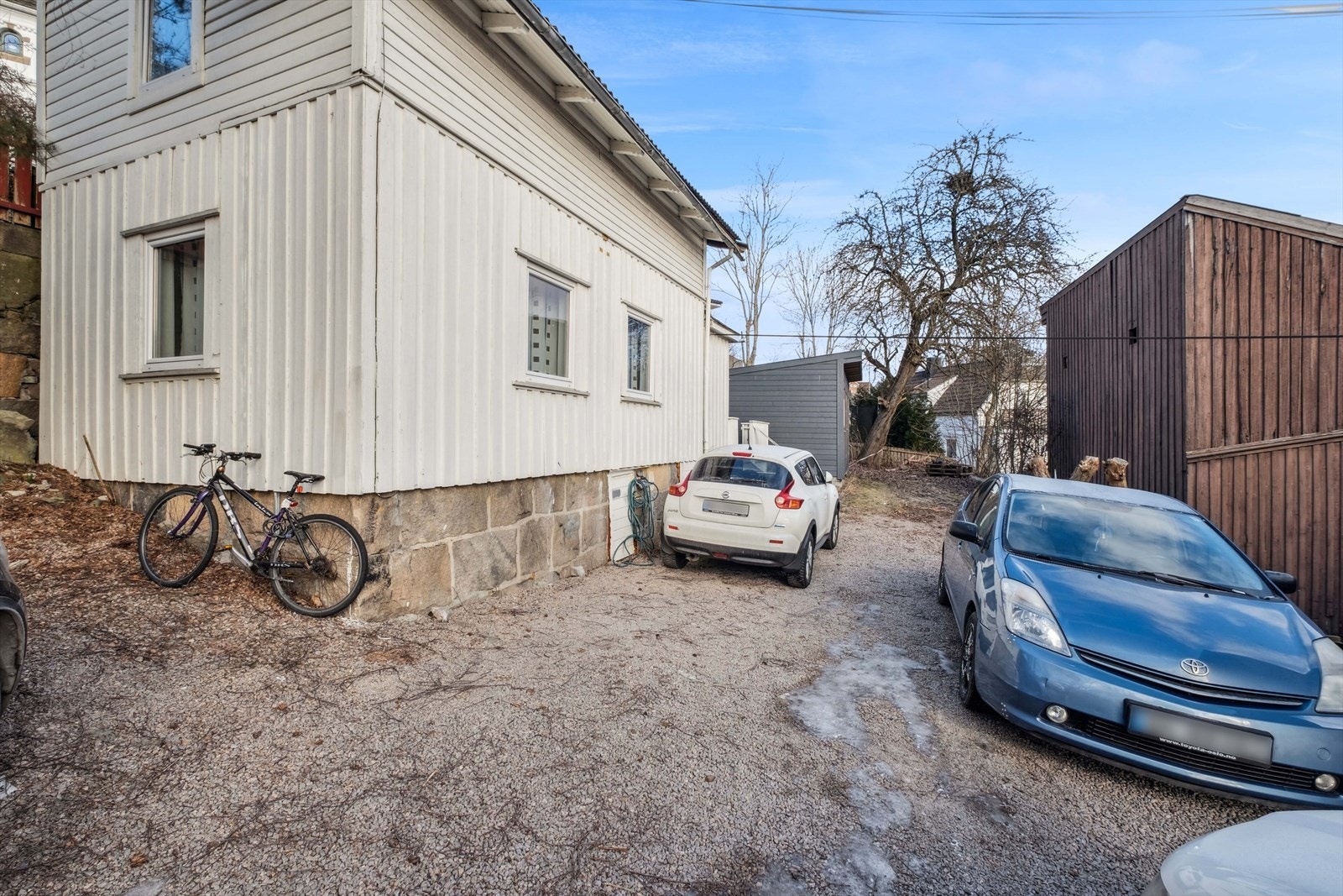 Det er parkering til flere biler i gruset gårdsplass. Galleribilde
