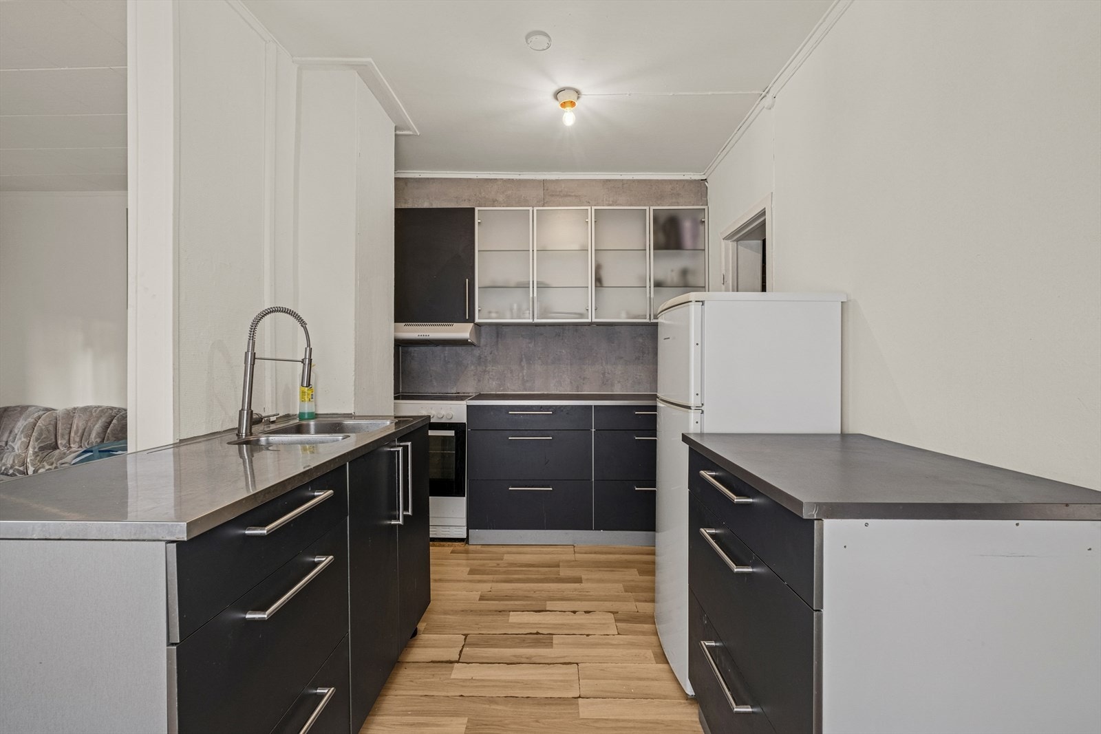 Kjøkkeninnredning med glatte fronter og laminat benkeplate med nedfelt kum i stål, samt opplegg for oppvaskmaskin. Galleribilde