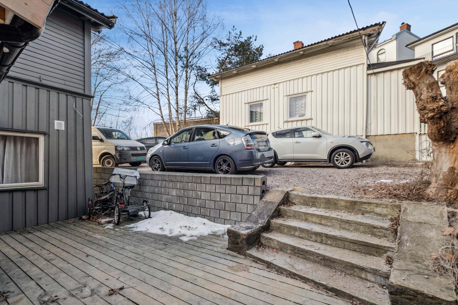 Forstøtningsmurer og trapp av betongstein er etablert mellom gårdsplass og boligen. Galleribilde