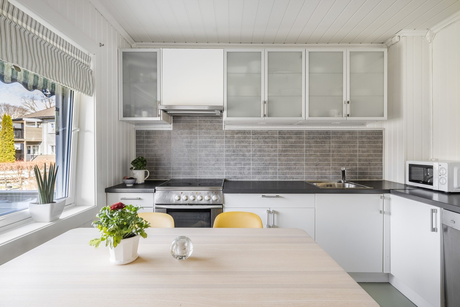Kjøkkenet har lys innredning med slette fronter og overskap med dører med glass. Galleribilde