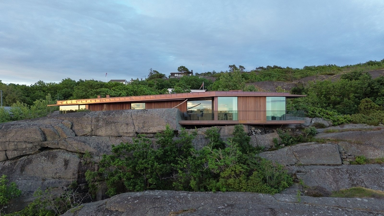 Hytta er fundamentert på stålsøyler i fjellet, med fasader kledd i mahognýplater og stående mahognýkledning. Galleribilde