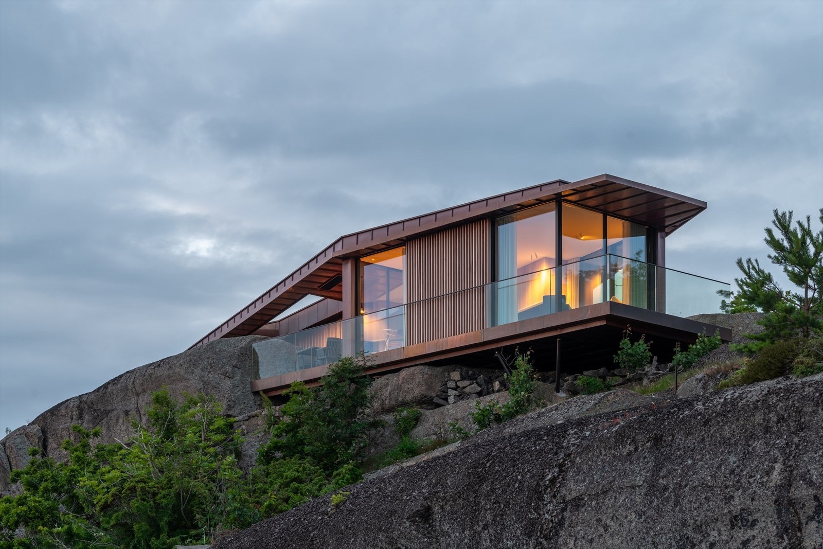 Store glassflater i aluminium og tre visker ut skillet mellom inne og ute, og rammer inn den omkringliggende naturen. Galleribilde