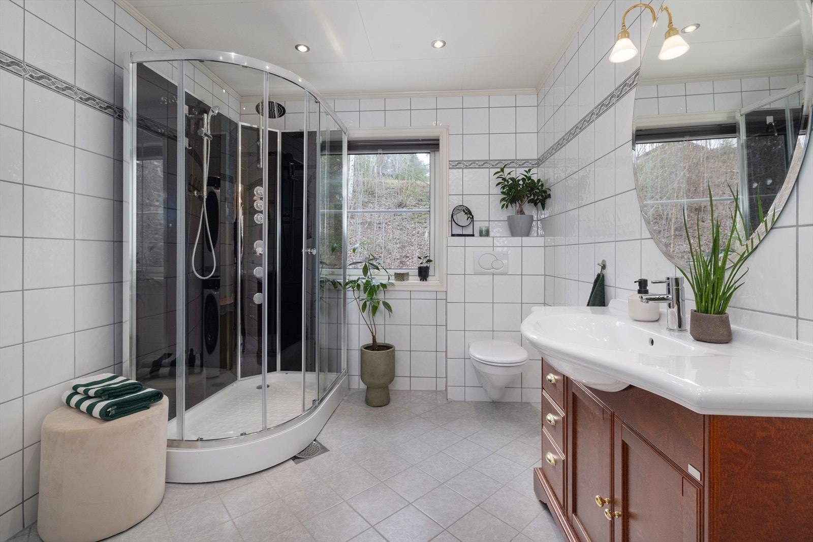 Badet er utstyrt med dusjkabinett, vegghengt toalett og en romslig servantinnredning. Galleribilde