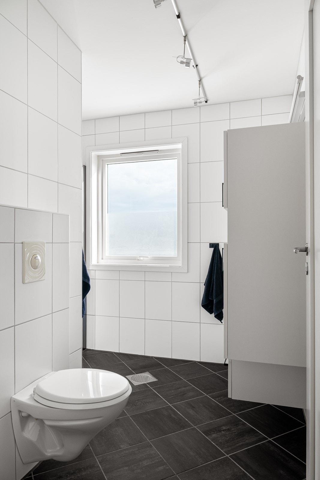 Badet er innredet med servant i baderomsmøbel med speil, veggmontert toalett og dusjvegger/hjørne Galleribilde
