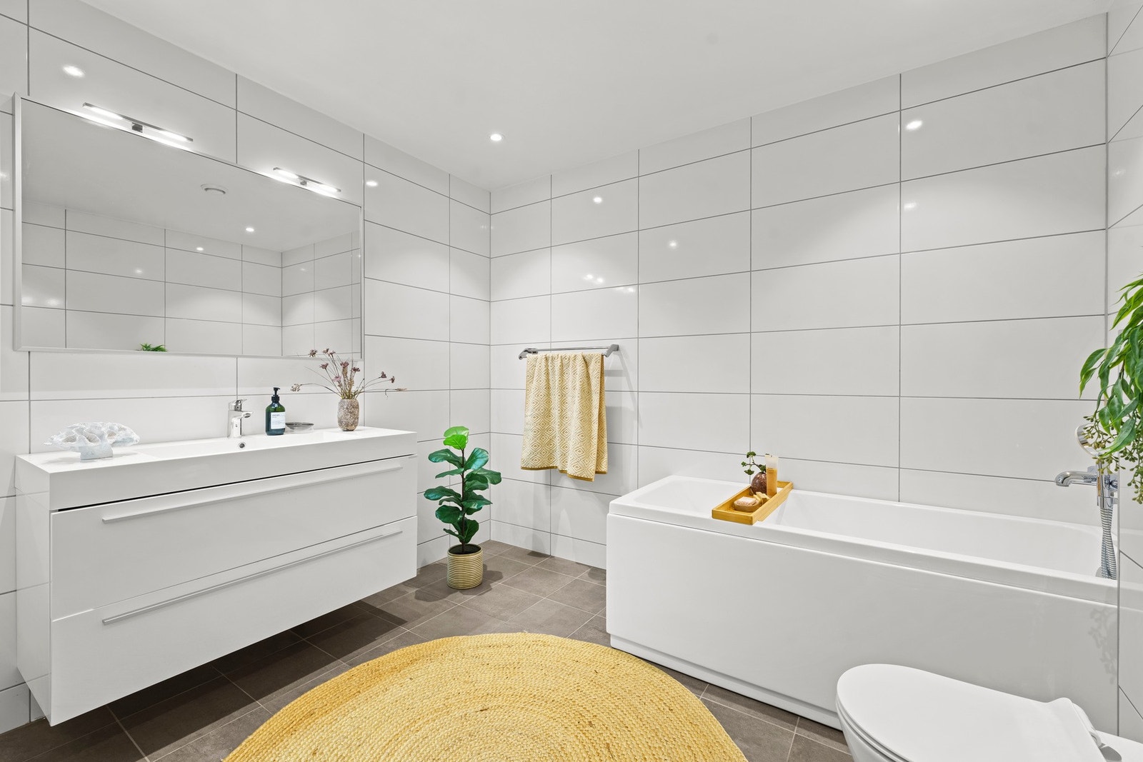 Badet er innredet med servant, vegghengt toalett og badekar, og gir god fleksibilitet i hverdagen for en familie. Galleribilde