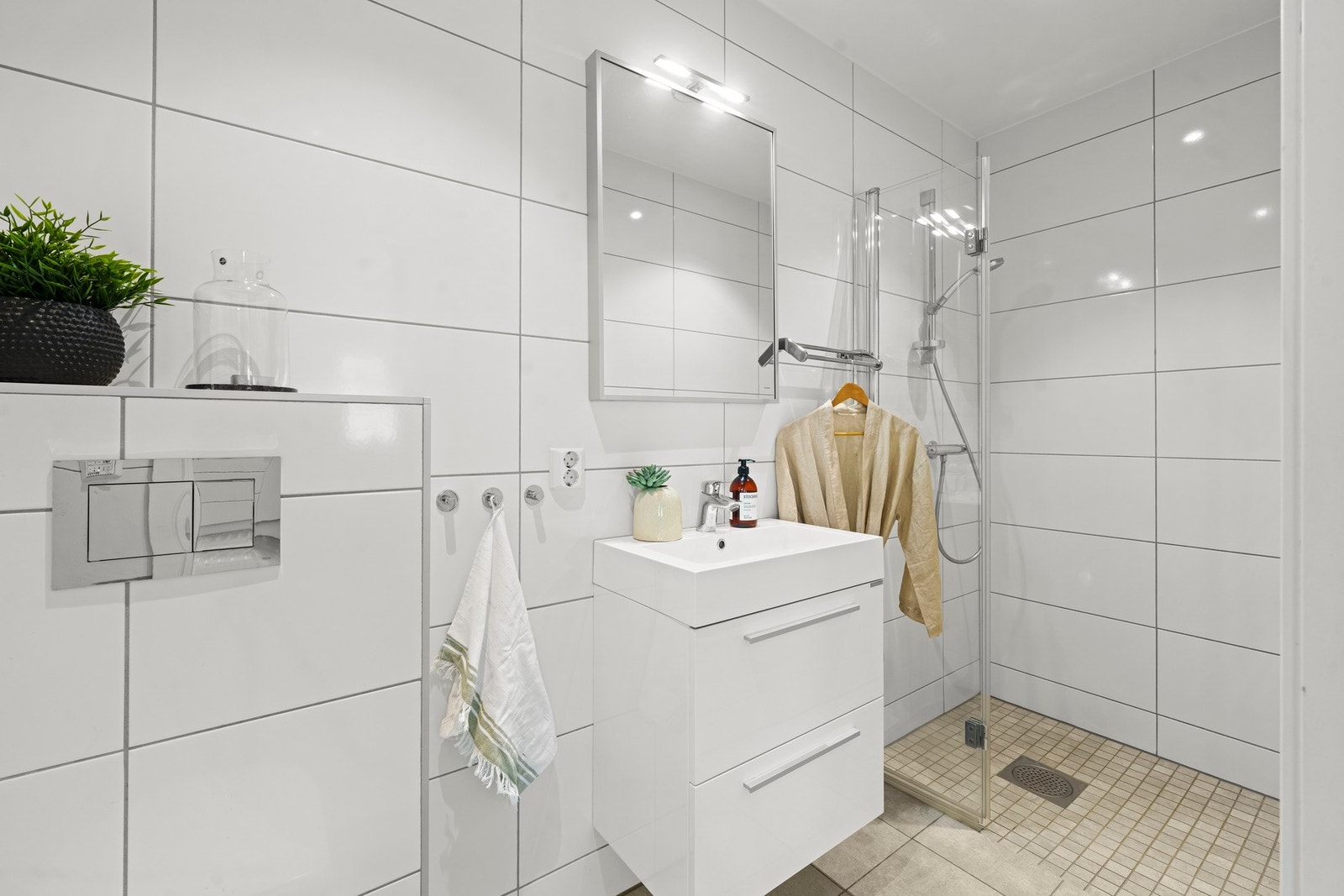Badet er utstyrt med dusjhjørne, vegghengt toalett og servant med innredning. Galleribilde