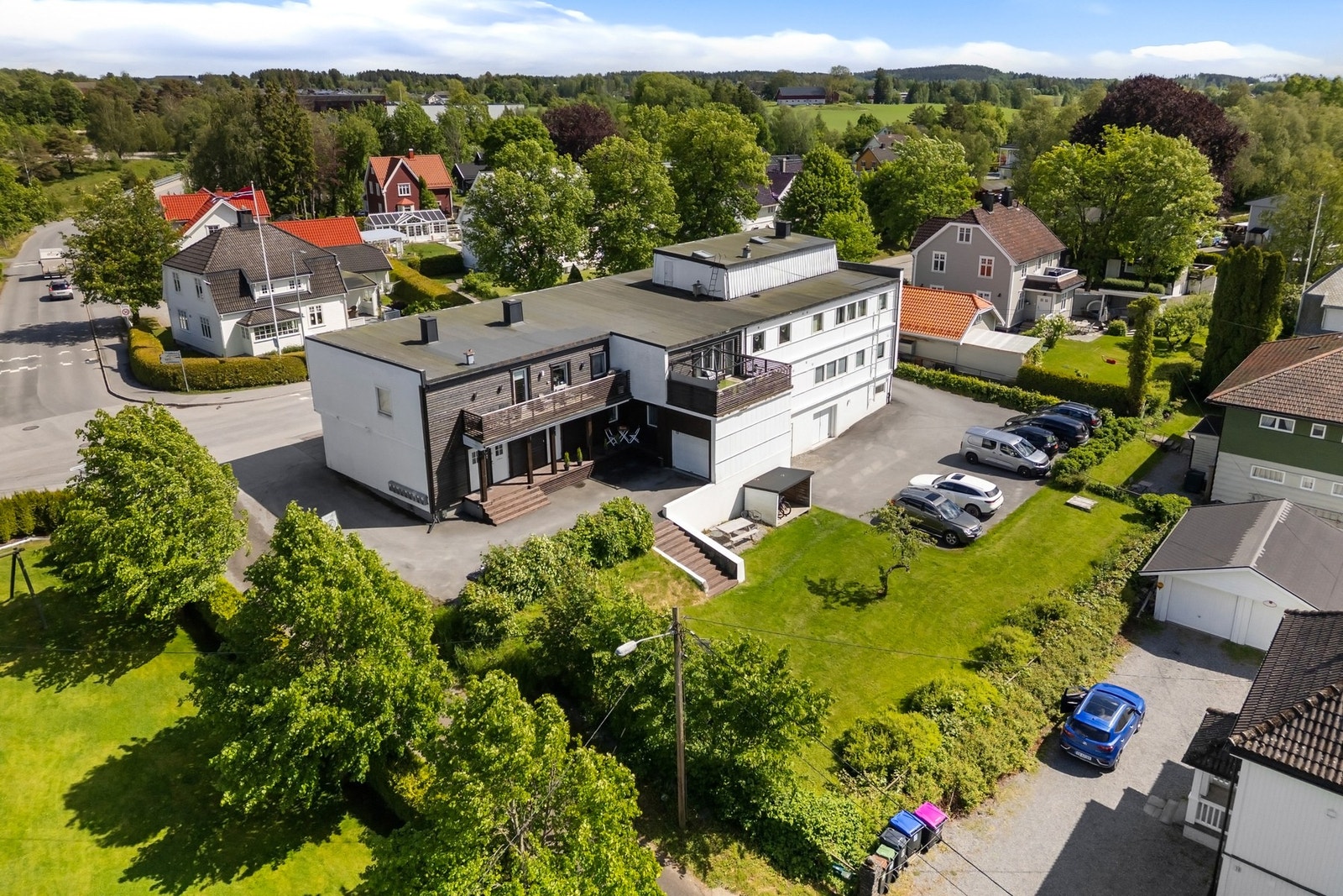 Motsatt fasadeside har hageareal og stor felles parkeringsplass Galleribilde