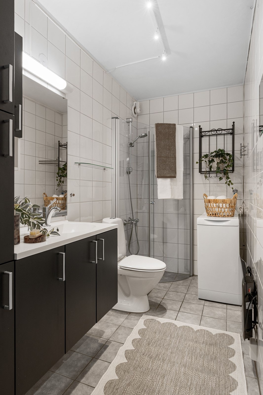 Baderommet er flislagt og har en romslig innredning med mye oppbevaringsplass. Badet er videre utstyrt med dusjhjørne, toalett og opplegg for vaskemaskin. Galleribilde