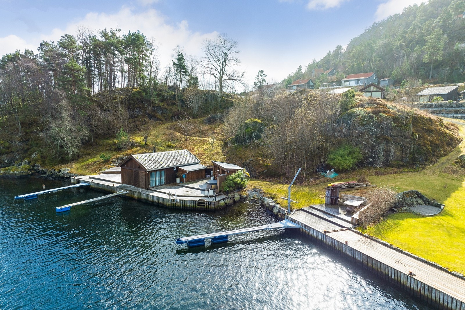 Like nedenfor hytta ligger sjøhuset hvor man også har egen bryggeplass med utrigger og et herlig oppholdsområde med grillplass, bord og benker Galleribilde