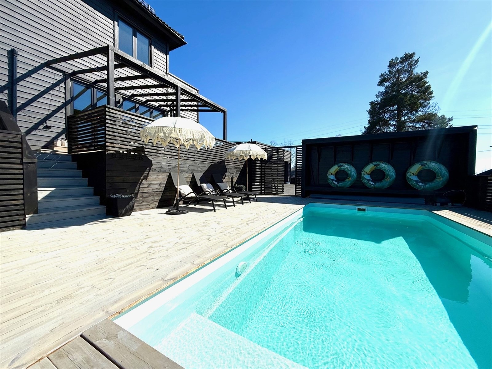 En trapp fra terrassen fører ned til det største nivået, bestående av et flott svømmebasseng med tilhørende loungedel med god plass til solsenger, sofagruppe, spisebord m.m. Galleribilde