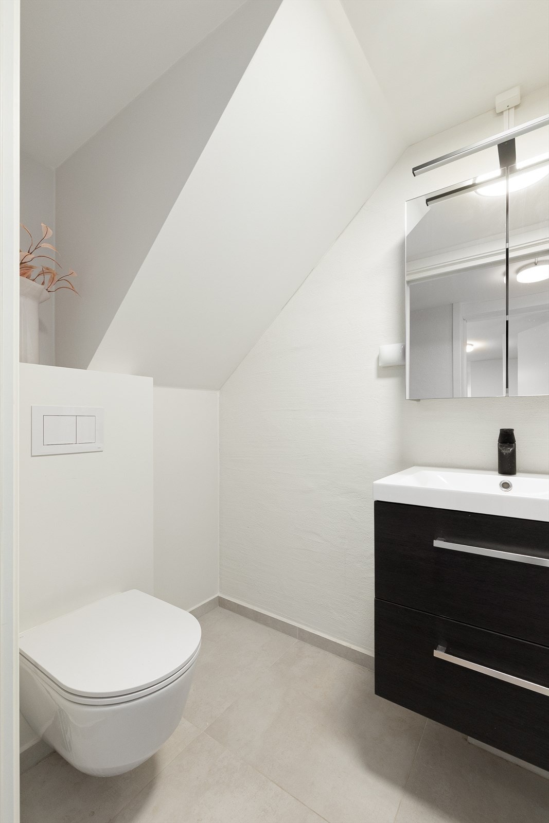 Badet er innredet med dusj med vannfallsdusj og hånddusj, servant i innredning med skuffer under, speil med belysning over samt vegghengt toalett Galleribilde