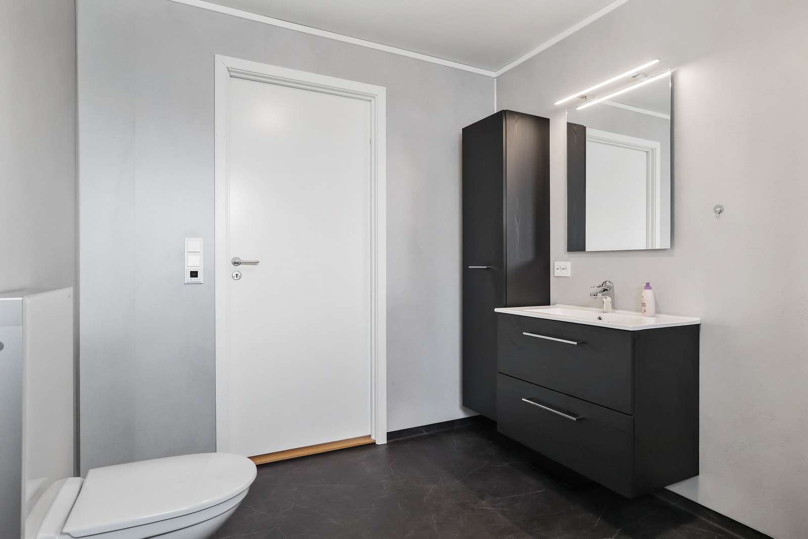 Rommet er utstyrt med en moderne baderomsinnredning med servant, vegghengt toalett og et praktisk dusjkabinett. Galleribilde