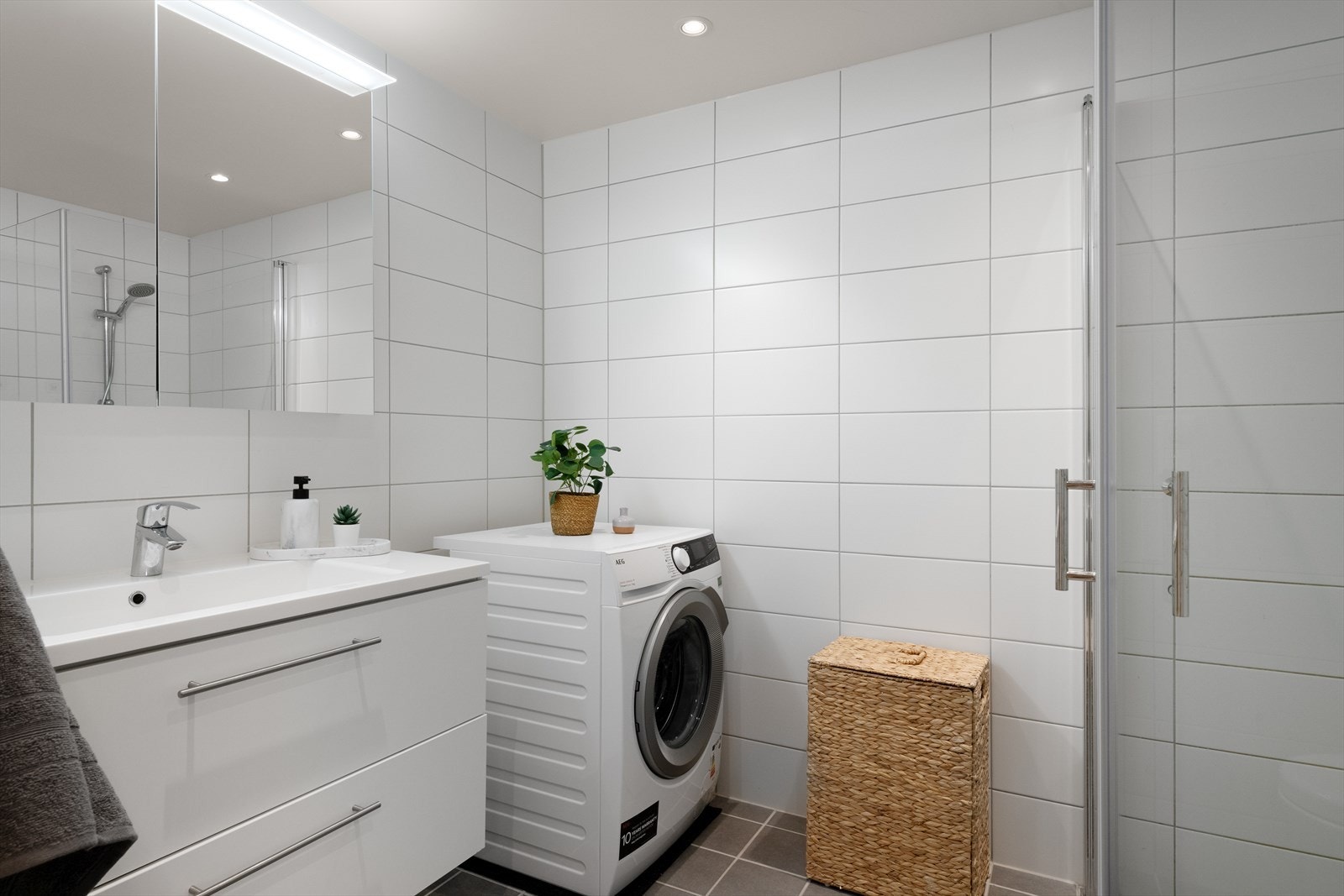 - Badet måler 4,9m² og er innredet med toalett, servantmøbel, speilskap med belysning, dusjhjørne med glassdører samt opplegg for vaskemaskin - Galleribilde