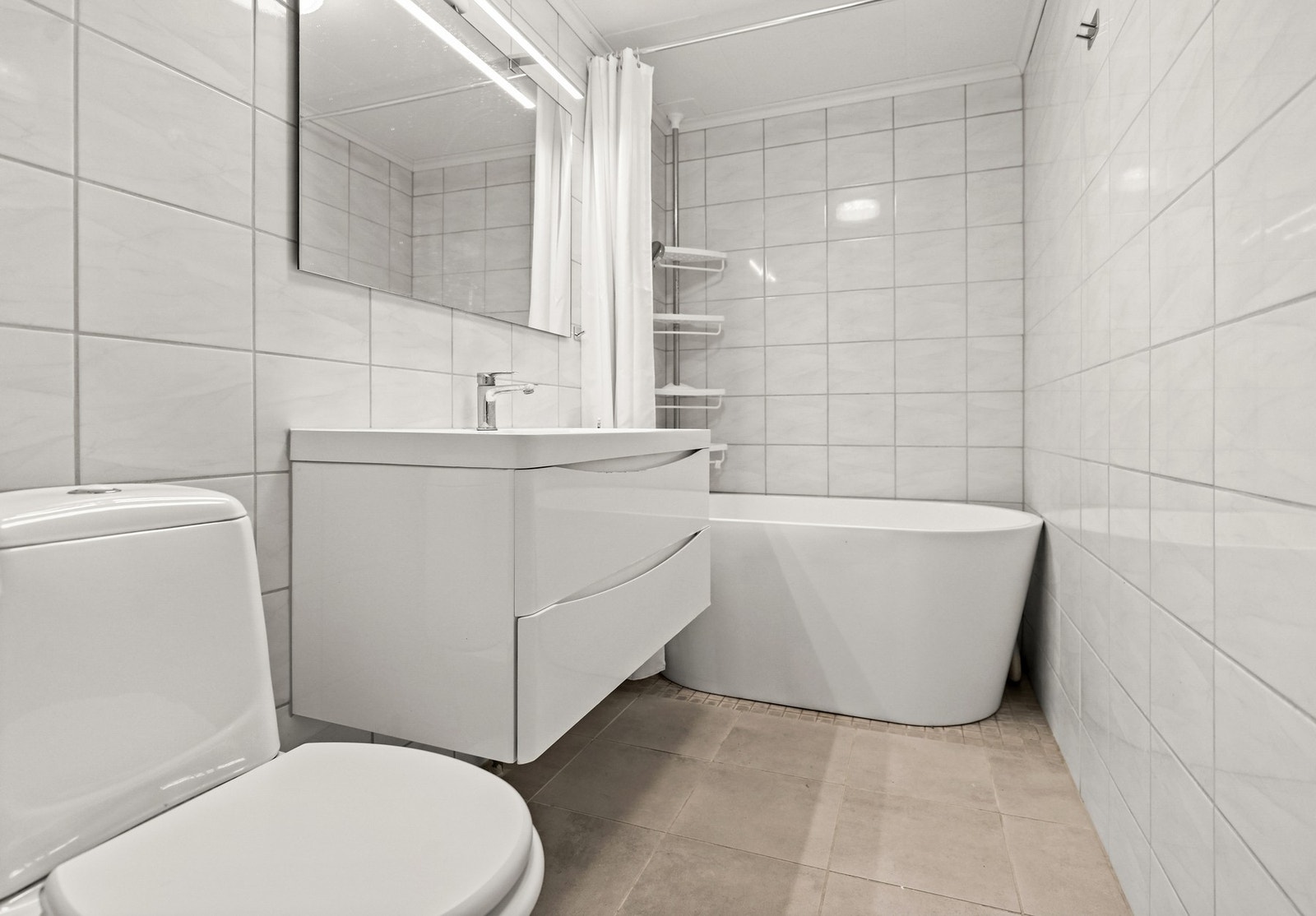 Boligen har et flislagt bad i underetasjen. Badet har gulvvarme og er innredet med servantskap, speil, badekar og gulvstående wc. Galleribilde