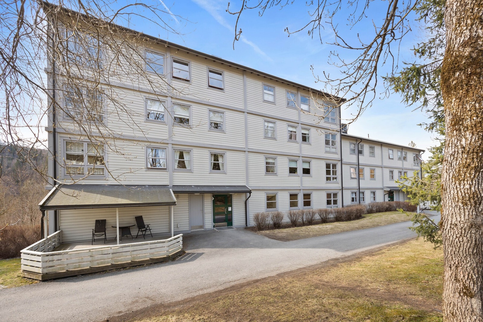 Fire-etasjers blokk med balkonger og hvitmalt fasade. Galleribilde