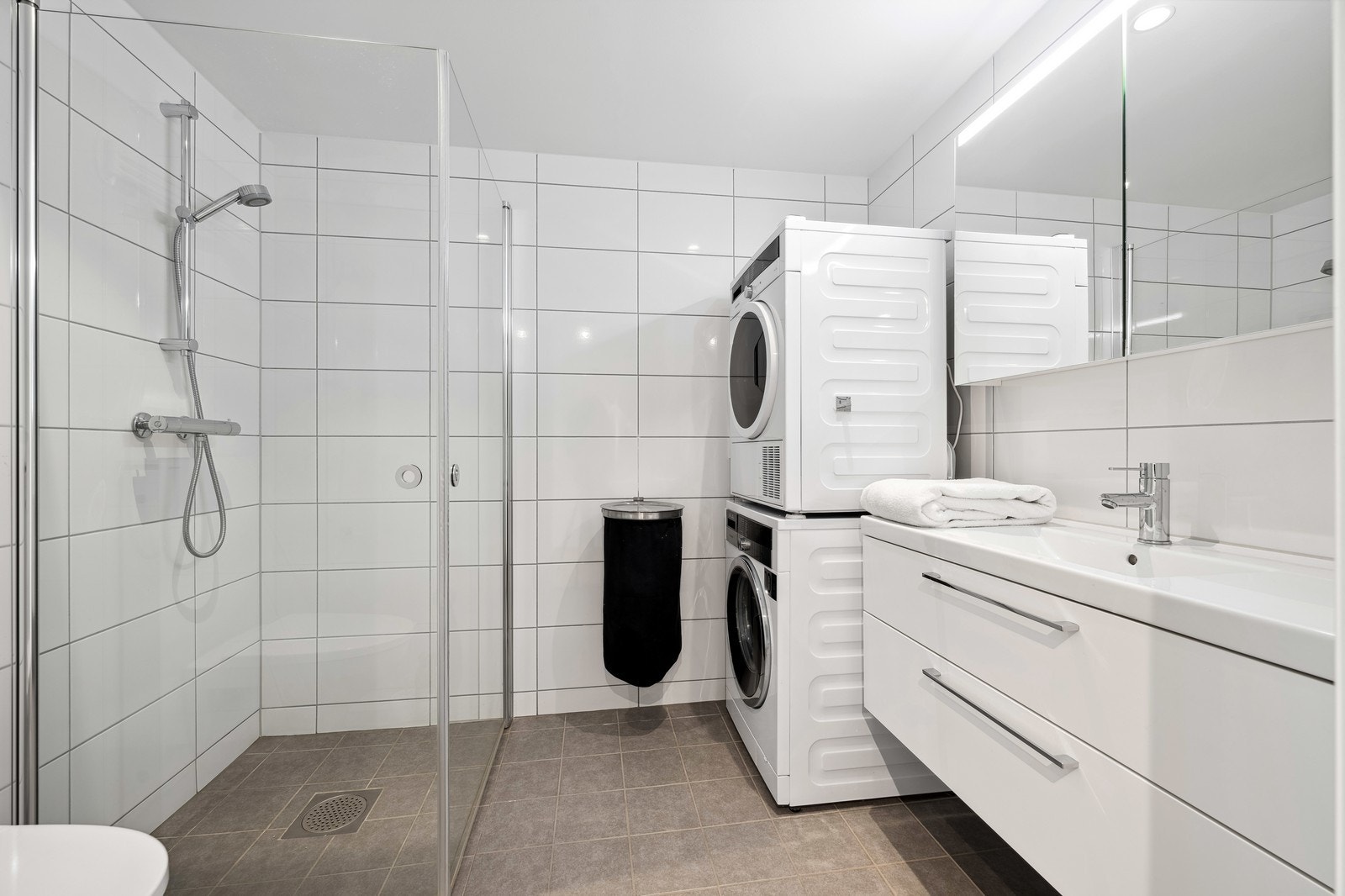 Pent bad med toalett, hjørnedusj og servant m/innredning. Vaskemaskin og tørketrommel følger med Galleribilde