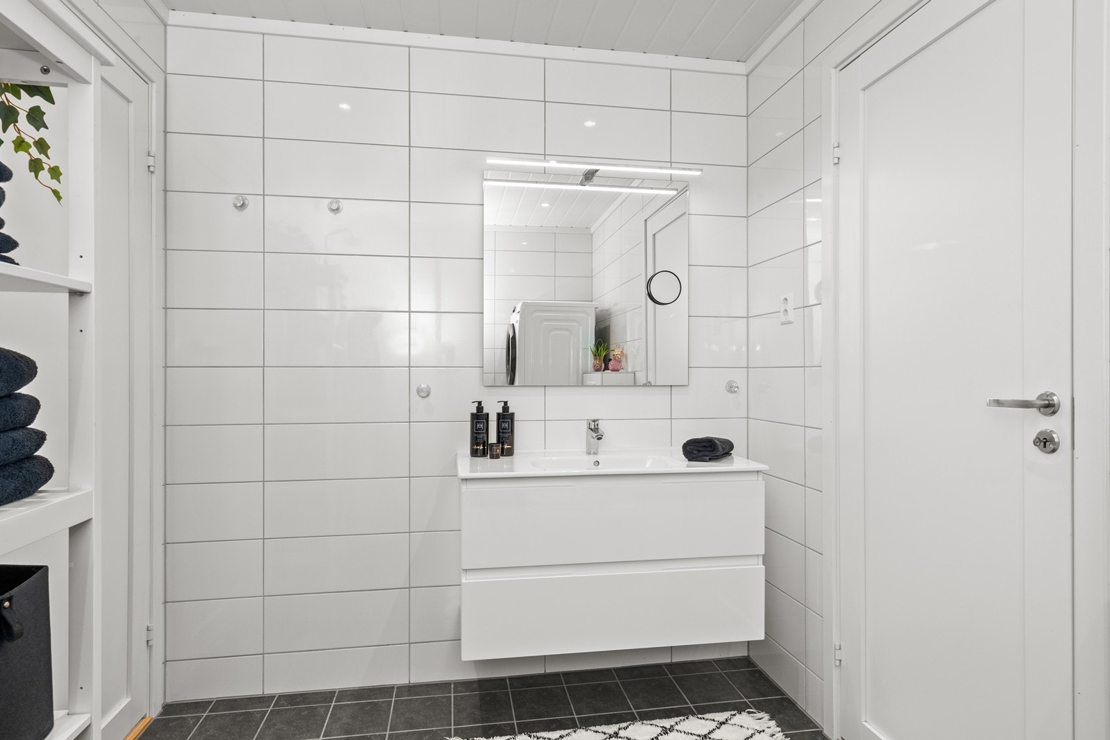 Badet har flislagt gulv med varmekabler, dusjhjørne og servant i innredning. Galleribilde