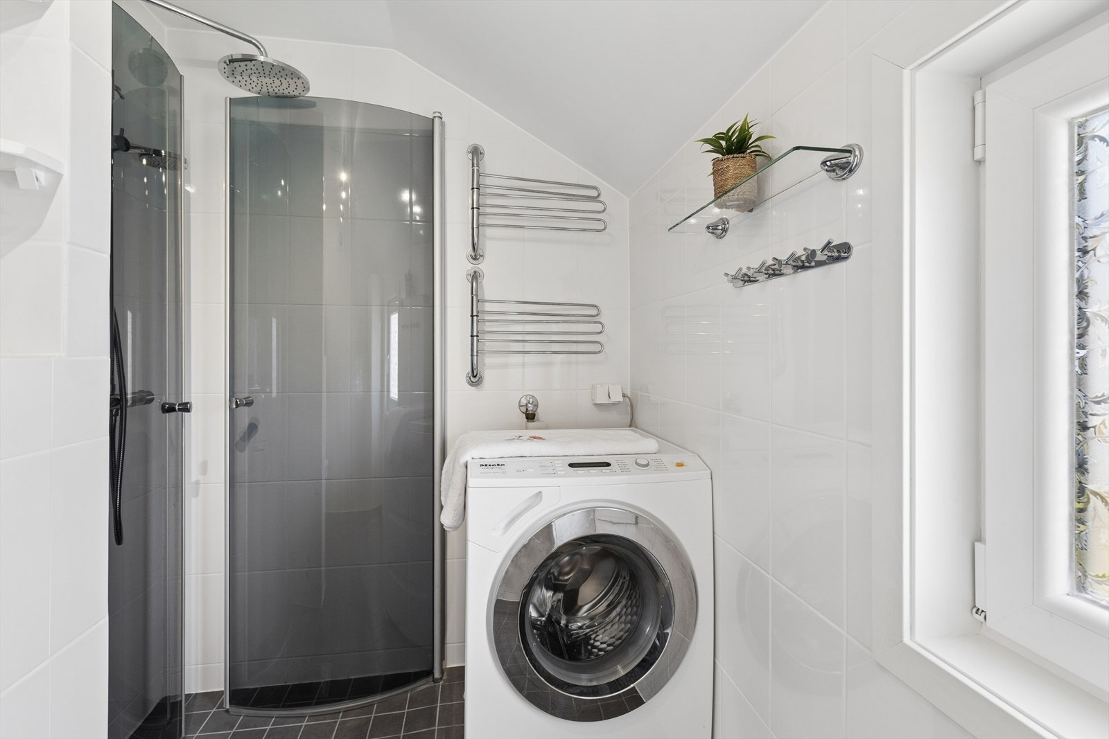 Innredningen består av en servant nedfelt i skap, speilskap, toalett med spylefunksjon og et dusjhjørne med glassdører, samt opplegg for vaskemaskin. Galleribilde