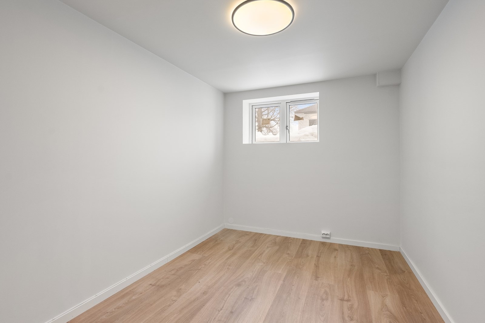 Innredet rom i kjelleren med laminatgulv og vindu. Hele etasjen ble pusset opp i 2023. Galleribilde