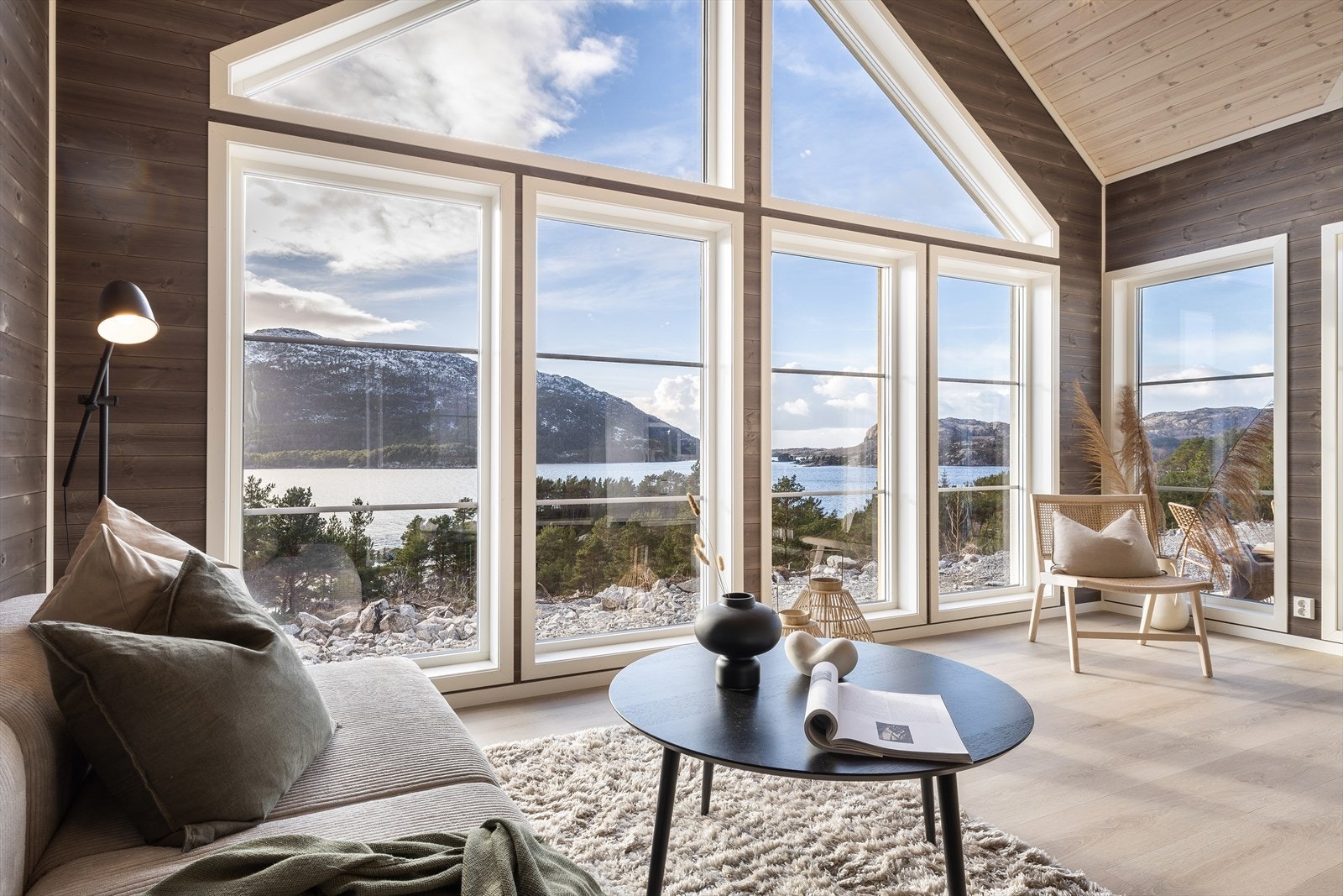 Store vindusflater slipper inn rikelig med dagslys og skaper en luftig, moderne atmosfære, mens det høye taket forsterker romfølelsen og gir hytten et innbydende preg Galleribilde