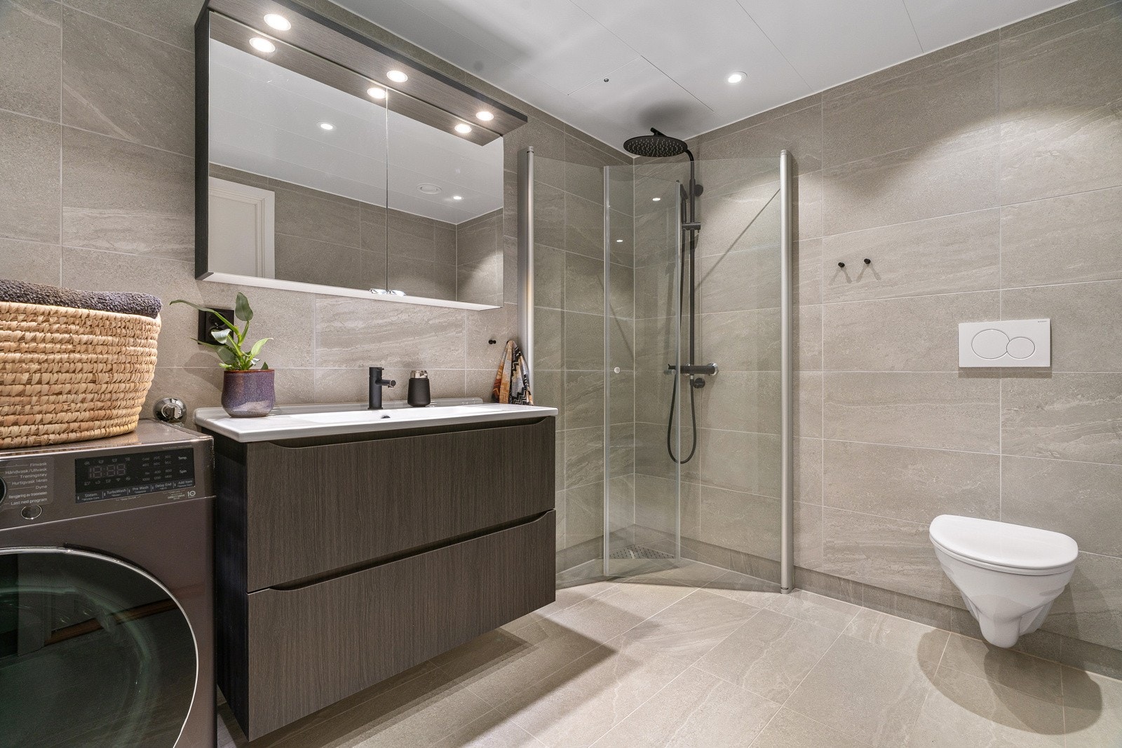 Delikat bad med oppgraderte fliser på gulv og vegger. Badet har gulvvarme, romslig dusjhjørne og et praktisk vegghengt toalett.