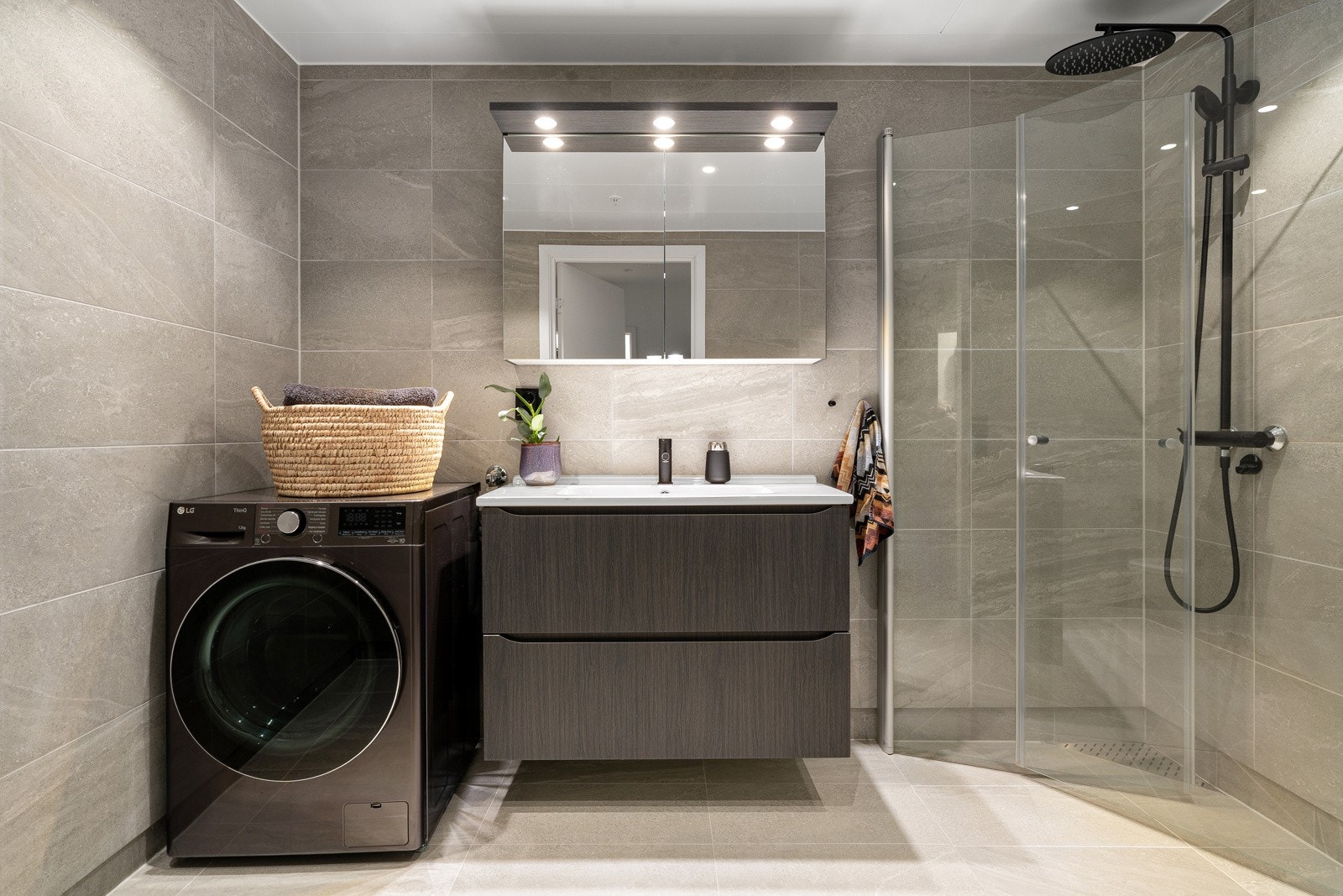 Stilrent uttrykk med speil- og servantskap i mørk eik, samt sort vask- og dusjgarnityr.